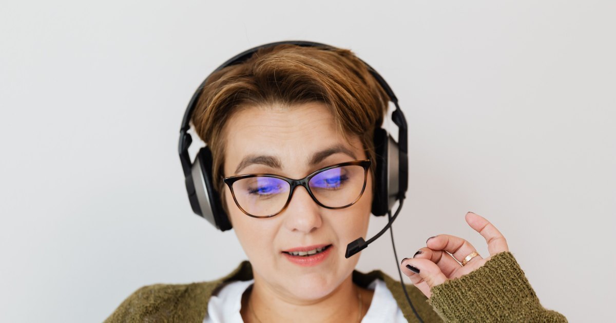 A tutor in a headset and glasses talking to a learner on her laptop